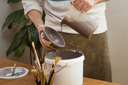Potter Glazes Bowls in Workshop. Ceramic Artist Man glazing on master class. Pottery Making process,...