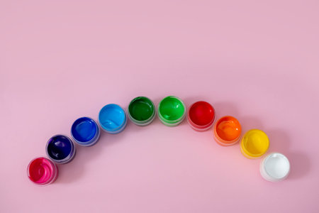 Multicolored paints on a pink background. Jars with multi-colored paints. Acrylic, gouache.の写真素材