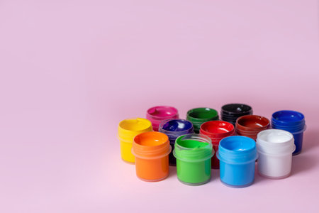 Multicolored paints on a pink background. Jars with multi-colored paints. Acrylic, gouache.の写真素材