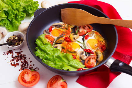 Fried eggs in pan with ingredients on wooden backgroundの写真素材