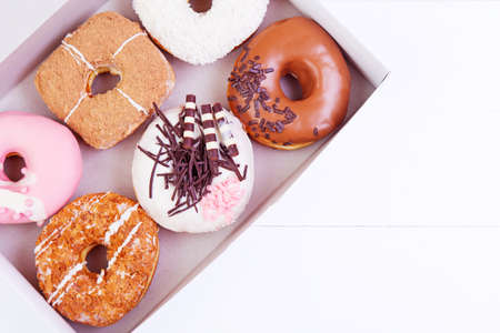 Colorful delicious donuts with coconut and other sprinkles in a box on a wooden backgroundの写真素材