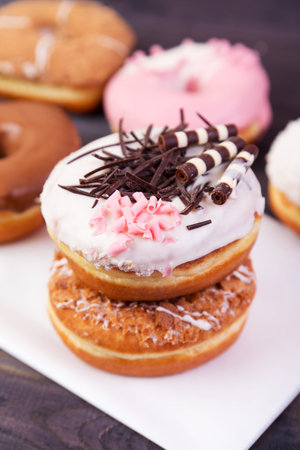 Colorful donuts with chocolate, glaze and sprinkles on a wooden tableの写真素材