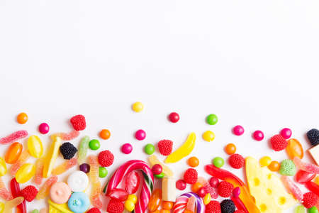 Mixed colorful candies, jellies and lolly pops on the white background. Top view with copy spaceの写真素材