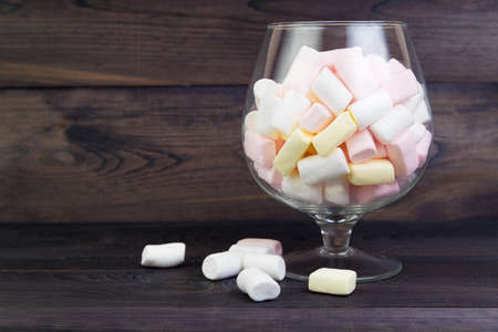 White and pink marshmallows in a large glass on the dark wooden backgroundの写真素材