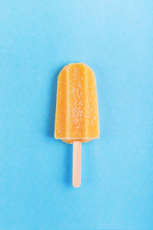 Single homemade orange ice sticks on a blue background. Top view with copyspaceの写真素材