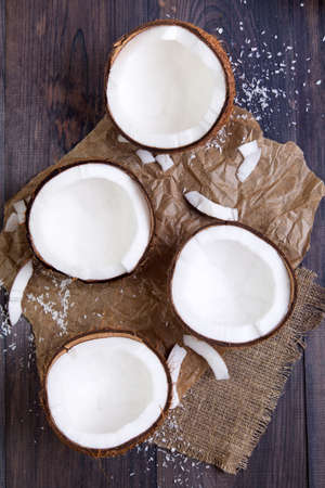 Fresh coconut halves with shell on a dark wooden table. Top viewの写真素材