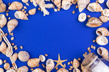 Colorful marine items - seashells, starfish, coral, bottle with note and rope arranged as frame. Top view with copyspaceの写真素材