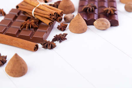 Broken chocolate bar with candy truffles, cinnamon and anise on a white wooden backgroundの写真素材