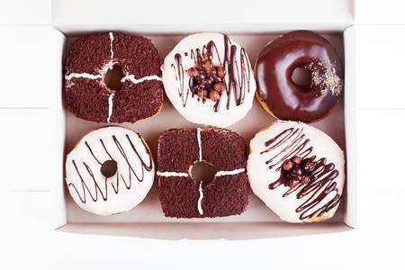 Colorful delicious donuts with sprinkles in a box on a white wooden background. Top view with copyspaceの写真素材