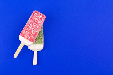 Strawberry and kiwi 
stick on a blue background. Top view with copyspace