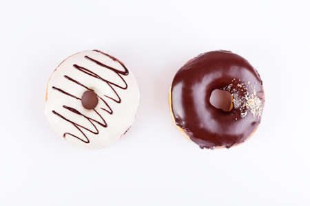 Two sweet donuts with chocolate glaze and sprinkles on a white background. Top view with copyspaceの写真素材