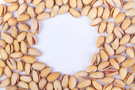Salted pistachios arranged as frame on a white background. Top view with copyspaceの写真素材