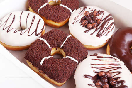 Chocolate delicious donuts with sprinkles in a box on a white backgroundの写真素材
