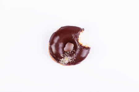 Chocolate bitten donut with glaze and sprinkles on a white background. Top view with copyspaceの写真素材