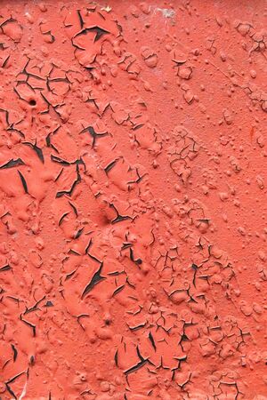 Old cracked red paint on a metal surface that has been painted many times.の写真素材