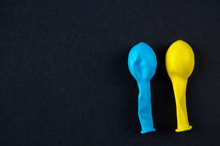 Two blue and yellow balloons on a black background. Space for text.の写真素材