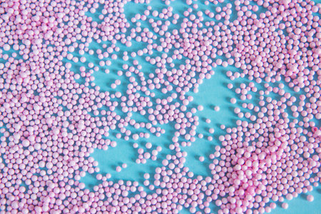 Pink and white sprinkles on a blue background. Top view.の写真素材