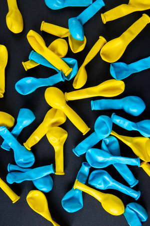 Blue and yellow balloons on black background. Top view. Flat lay.の写真素材