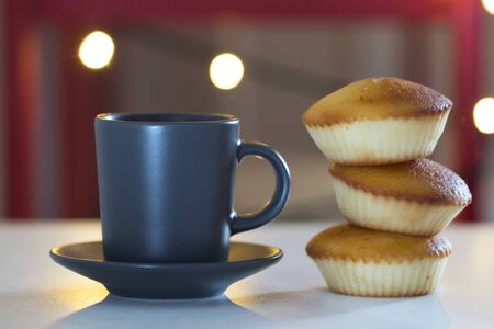 Black cups and cupcakes on the white tableの写真素材