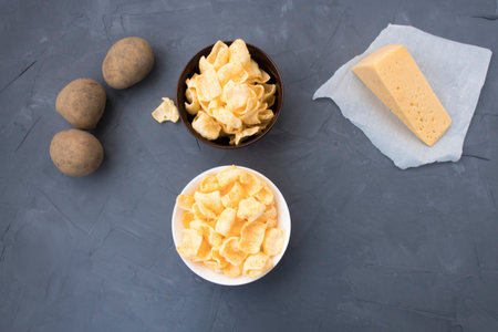 Potato chips with cheese in a plate that is located on a gray background.の写真素材