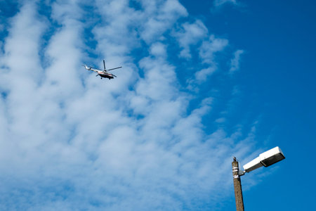 helicopter flies high in the sky against a background of clouds