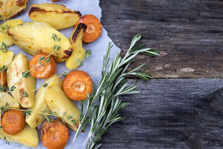 Appetizing baked vegetables, potatoes and carrots with thyme, rosemary and spices and copy space.の写真素材
