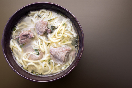 Soup noodles with meat in a plate on a dark background close-up and copy spaceの写真素材