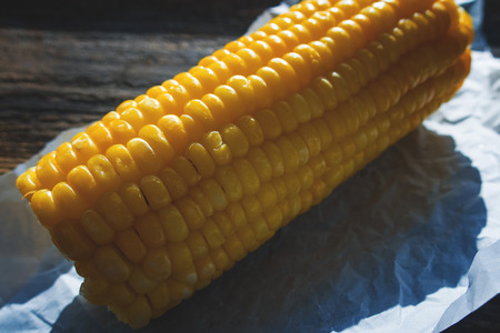 Boiled corn close-up on food paper and on an old wooden backgroundの写真素材