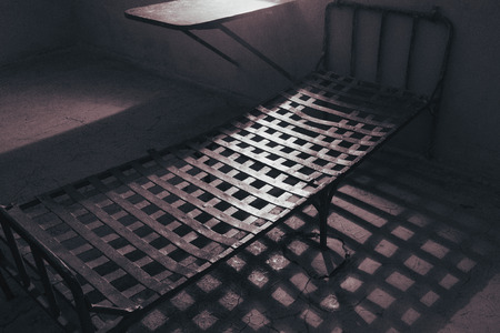 An old prison cell, an iron bed and a tableの写真素材
