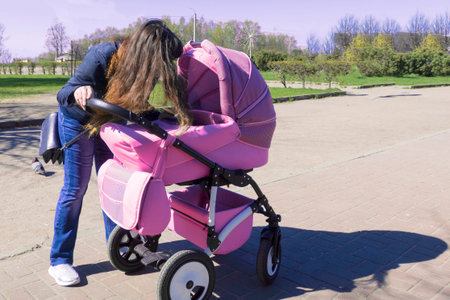 A woman on a street in a summer city Bent down and looks in the stroller to her baby