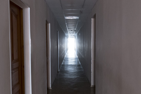 A long corridor with doors at the sides and a light at the end of the corridorのeditorial素材