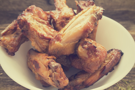 Appetizing fried chicken pieces, close-up, in a white plate on a wooden background.の写真素材