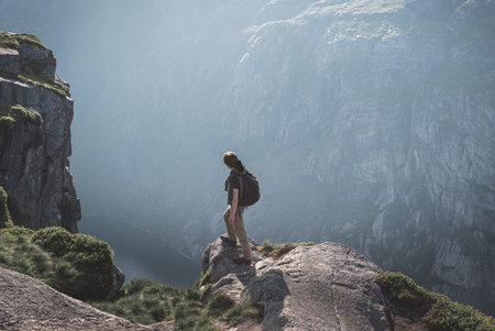 Hiker standing on the edge of a cliff and enjoying the view. Hiking trail in Norway on the Kjerag plateauの写真素材