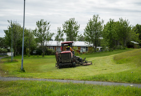 large lawn mower mowing grass on a green field