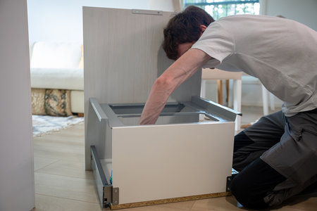 Man cleaning kitchen cabinet with sponge in kitchen roomの写真素材