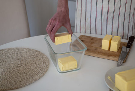 human hand puts butter into a glass jar. Cooking ghee oil