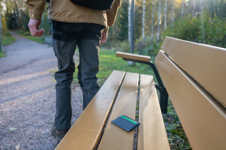man is leaving from a bench where he lost his credit card holder. Forgotten credit card holder on a park bench.の写真素材