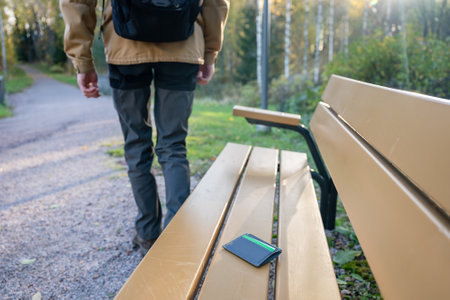 man is leaving from a bench where he lost his credit card holder. Forgotten credit card holder on a park bench.の写真素材