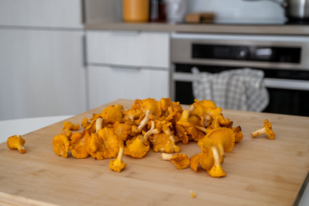Whole chanterelle mushrooms arranged on a wooden cutting boardの写真素材