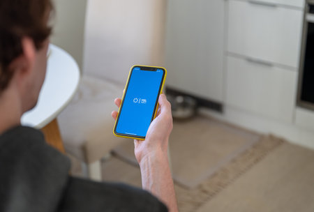 Espoo, Finland - October 29, 2024: Man holding iPhone with app HSL on the screen, using mobile application at homeのeditorial素材