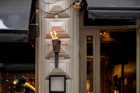 Torch with flame on a building entrance with warm light ambiance.の写真素材