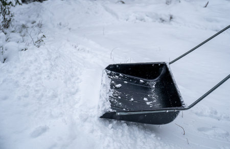 person clearing snow with a large snow shovel on a snowy pathway. concept of outdoor choresの写真素材