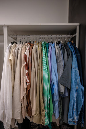 Variety of clothing on hangers organized on a rackの写真素材
