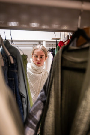 Woman clothes browsing in a thrift shop. Second hand concept