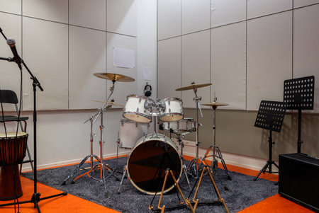 drum set with cymbals in a music rehearsal room with acoustic panels, microphone, and music stands, creating a professional practice spaceの写真素材