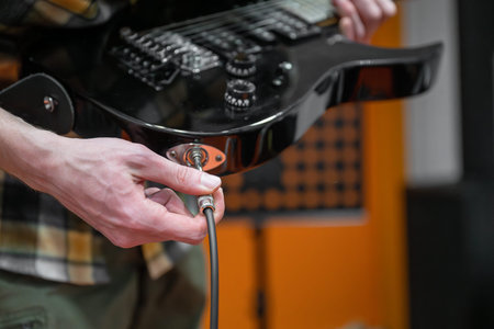 Person plugging in electric guitar cable in the music studioの写真素材