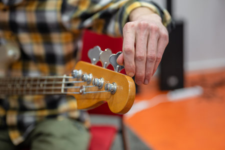 Close up of man tuning guitar headstock detail in recording studio.の写真素材