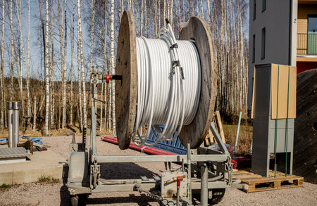 Huge industrial wooden cable spool with coiled white cable on a mobile trailerの写真素材