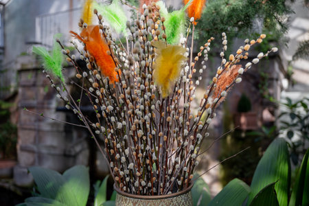 Pussy willow branches with colorful feathers in spring sunlight close-up