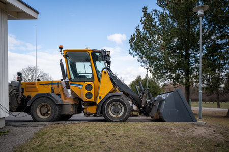 Yellow front loader parked by roadside near forested areaの写真素材